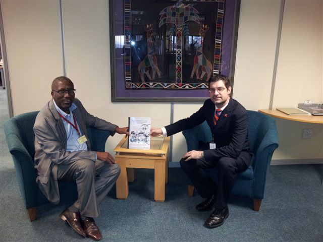 Prof Geo Quinot (right) presents the research report titled "An Institutional Legal Structure for Regulating Public Procurement in South Africa" to Mr Henry Malinga, Chief Director: Policy and Strategy in the OCPO.
